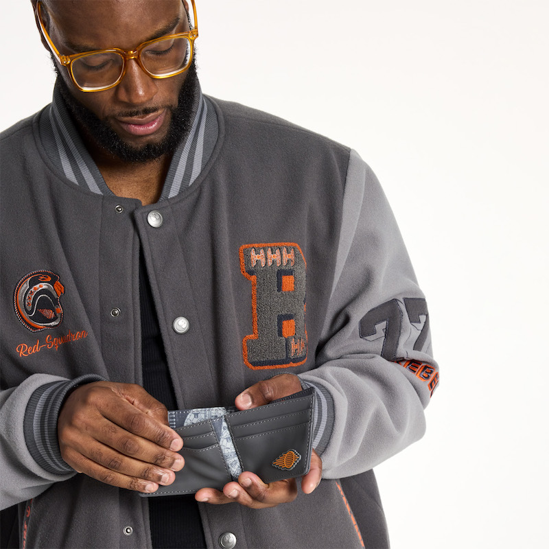 Bearded man with glasses wearing the Loungefly COLLECTIV Star Wars Rebel Alliance VRSITY Jacket and holding open the Loungefly COLLECTIV Star Wars Rebel Alliance The MINIMALST Wallet, showing off the card slots inside 